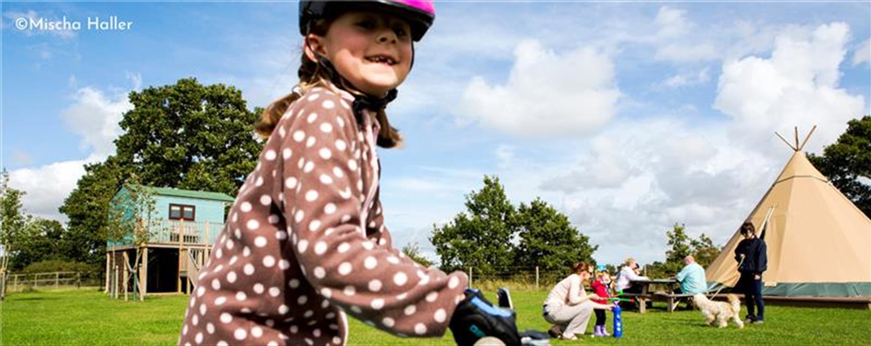 Girl riding a bike in front of wigwam tents